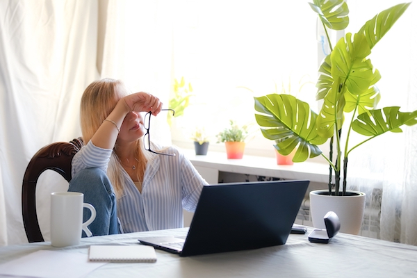 Stress abbauen: Frau sitzt stöhnend vor Laptop